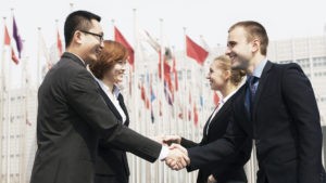 Four smiling business people meeting and shaking hands outdoors, Beijing